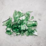 A broken green glass bottle in a pile on the floor used by The Break Room 831